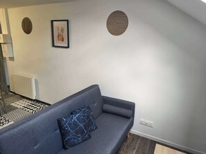 Ein modernes Wohnzimmer mit einem grauen Sofa, einem schwarz-weißen Teppich und einem gerahmten Kunstwerk an der Wand.