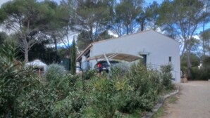 Ein weißes Gebäude mit einer Veranda, umgeben von üppiger Vegetation und Bäumen.