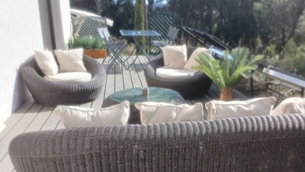 Eine Terrasse mit Korbmöbeln, darunter eine Couch und Stühle, sowie ein kleiner Tisch.