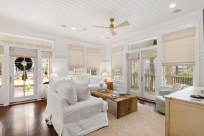 A spacious living room with a white sofa, a wooden coffee table, and a ceiling fan.