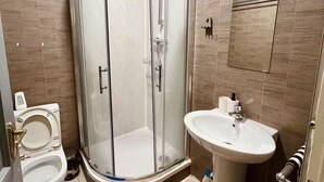 Une salle de bain moderne avec une douche à parois de verre, des toilettes blanches, un lavabo et un porte-serviettes.
