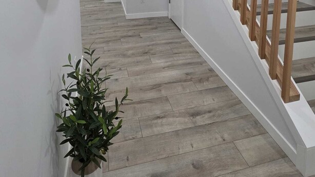 Un interior moderno con una escalera de madera, paredes blancas y un espejo con marco de madera.