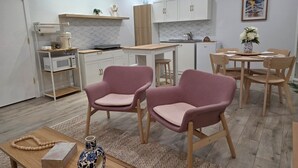 Una cocina moderna con armarios blancos, encimera de madera y comedor con sillas rosas y una mesa de madera.