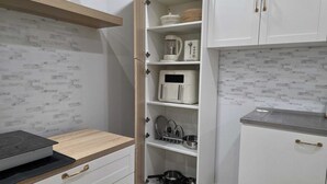 Una cocina compacta con armarios blancos, microondas integrado y cafetera.