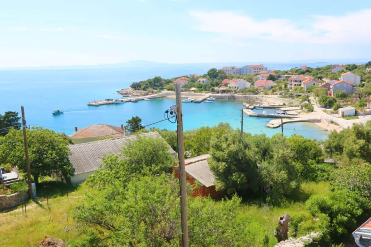 A coastal town with a marina, houses with red roofs, and lush greenery.