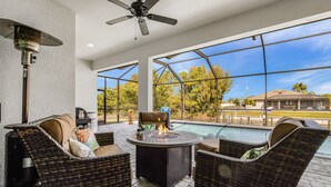 An outdoor patio with wicker furniture, a fire pit, and a view of a swimming pool. - Waterfront Dream! Saltwater Pool, Sauna, & Boat dock 4 bed 3 bath on the water (Cape Coral)