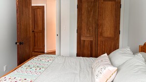 Une chambre à coucher avec un lit, deux portes en bois et un luminaire au plafond.