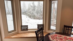 Un espace repas offrant une vue sur un paysage enneigé grâce à de grandes fenêtres.
