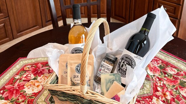 Une cuisine avec des meubles en bois, un four à micro-ondes et une machine à café. Un panier en osier contenant des bouteilles de vin et un bocal d’épices est posé sur le comptoir.