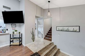 Een modern interieur met een trap, een wandtelevisie, een cactus en een lijstwerk.