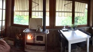 Une pièce chaleureuse avec un poêle à bois, une table à manger et de grandes fenêtres.