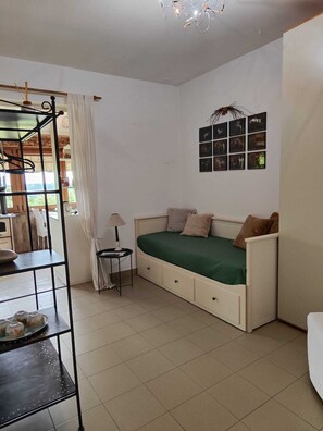 A room with a bed, a small table, a shelf, and a wall with framed pictures. - Farmhouse Tenuta Blueberry - Glicine near Milan-Malpensa (Cascinetta)