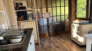 Une cuisine avec un plancher en bois, une cuisinière, un évier et une fenêtre donnant sur un paysage verdoyant.