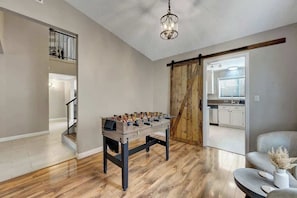 A spacious living room with a wooden foosball table, a comfortable seating area, and a view into the kitchen. - Prime and Relax Abode (Henderson)