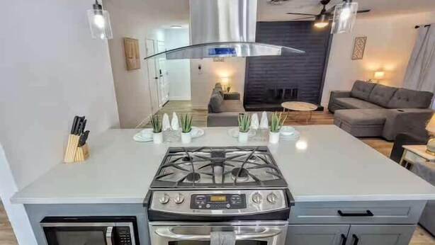 Uma cozinha moderna com ilha central, forno embutido e fogão.