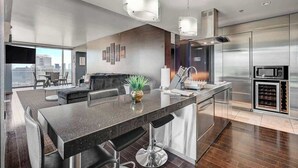 Una cocina moderna con una isla grande, electrodomésticos de acero inoxidable y vistas a la ciudad.