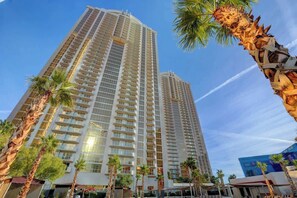 A high-rise hotel with multiple balconies, palm trees, and a clear sky. - Signature Strip View Suite (Las Vegas)