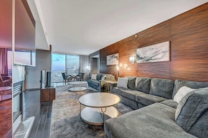 Ein modernes Wohnzimmer mit einem grauen Sofa, einem runden Couchtisch und einem Fernseher auf einem Holzboden.