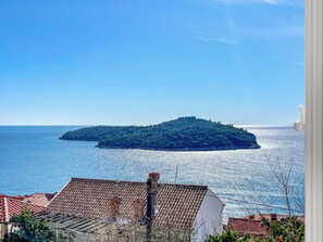 Eine Küstenansicht mit einer kleinen Insel in der Ferne, umgeben von klarem, blauem Wasser.