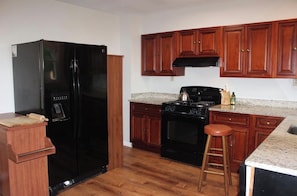 A kitchen with wooden cabinets, a black refrigerator, a stove, and a countertop.