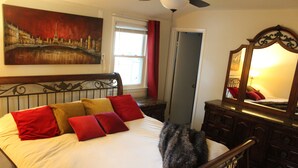 A bedroom with a bed, a mirror, a dresser, and a painting of a cityscape. - Inviting Lanham Suite - Quiet and Close to DC! (Lanham)