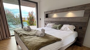 A modern hotel room with a large bed, a wooden headboard, and a view of the outdoors. - Villa Venti (lieu dit Barbagiolo)