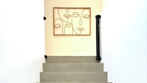 A staircase with a minimalist design, leading to a room with a plain wall and a framed artwork. - Villa Venti (lieu dit Barbagiolo)