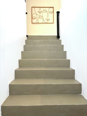 A staircase with a minimalist design, leading to a room with a plain wall and a framed artwork. - Villa Venti (lieu dit Barbagiolo)