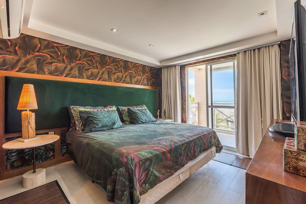 Ein Schlafzimmer mit Bett, Nachttisch, Lampe, Fernseher und Blick ins Freie.