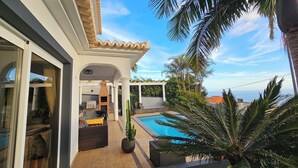 A poolside area with a patio, a built-in barbecue, and a view of the sea. - Great vacation home in Madeira, ocean view, in Ponta-do-Sol, heated pool (Ponta do Sol)