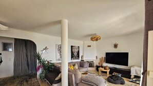 A modern living room with a sofa, ottoman, and a television. - Great vacation home in Madeira, ocean view, in Ponta-do-Sol, heated pool (Ponta do Sol)