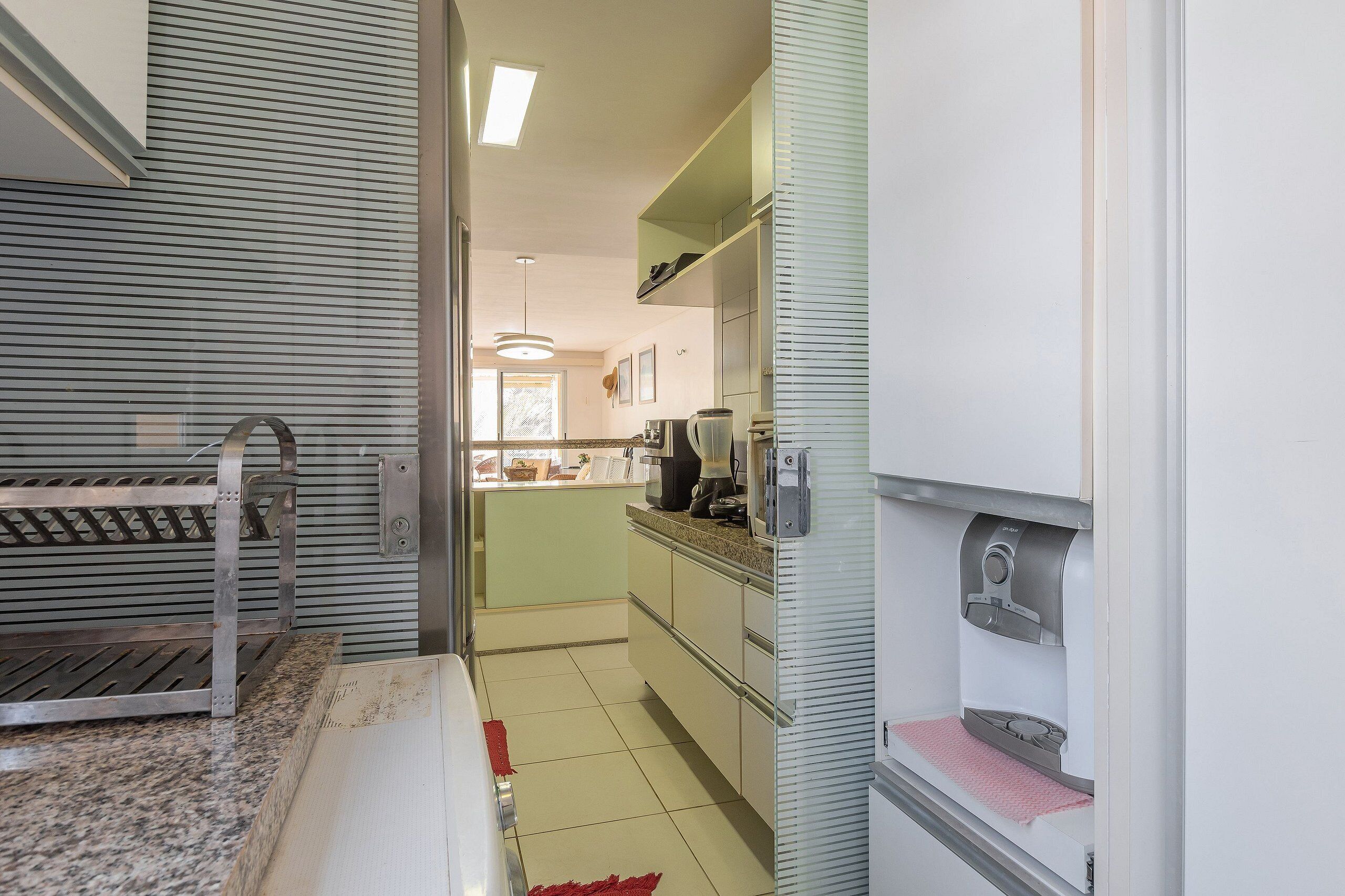 Una cocina compacta con lavamanos, encimera y cafetera.