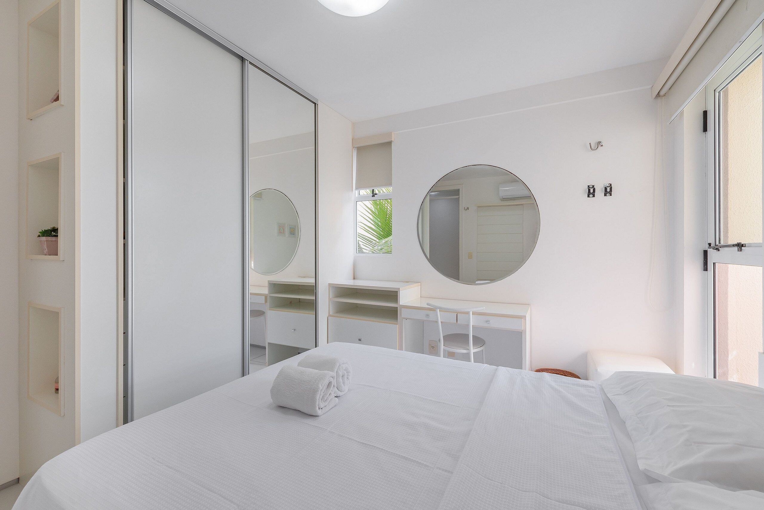 A modern hotel room with a large bed, a desk, and a mirror.