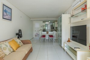 A modern living room with a sofa, TV, and a dining area with chairs and a table.