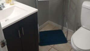 Ein Badezimmer mit einem weißen Waschbecken, dunklen Schränken, einer Toilette und einem Handtuchhalter mit gefalteten Handtüchern.