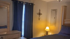 Ein Schlafzimmer mit Bett, Schminktisch, Nachttisch, Deckenventilator und Wandleuchte.