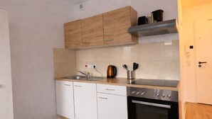 Une cuisine de taille réduite avec des meubles blancs, un four en acier inoxydable et un plan de travail en bois.