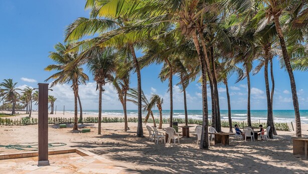A beachside patio with palm trees, a tiled floor, and outdoor seating. - Portamaris Resort - Luxury Apartment by Carpediem (Aquiraz)