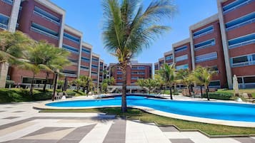 Un hotel con piscina, palmeras y un cielo azul despejado.