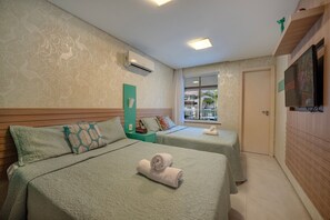 Ein Hotelzimmer mit zwei Betten, einem Fernseher, einer Klimaanlage und einem Fenster mit Blick.