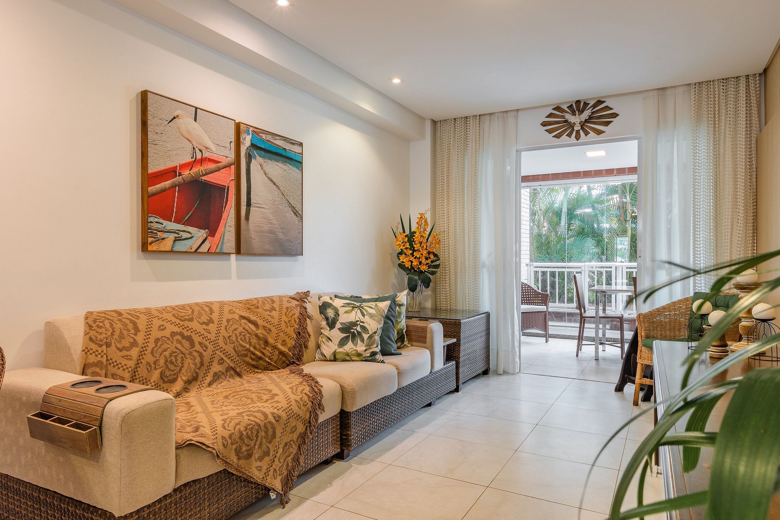 Una sala de estar con sofá, una mesa de centro y un comedor con sillas y una mesa. Se ve una ventana con cortinas y vistas al exterior con vegetación.