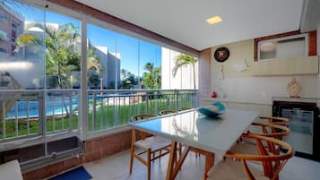 Una cocina moderna con comedor, ventanas amplias y vista a una piscina.