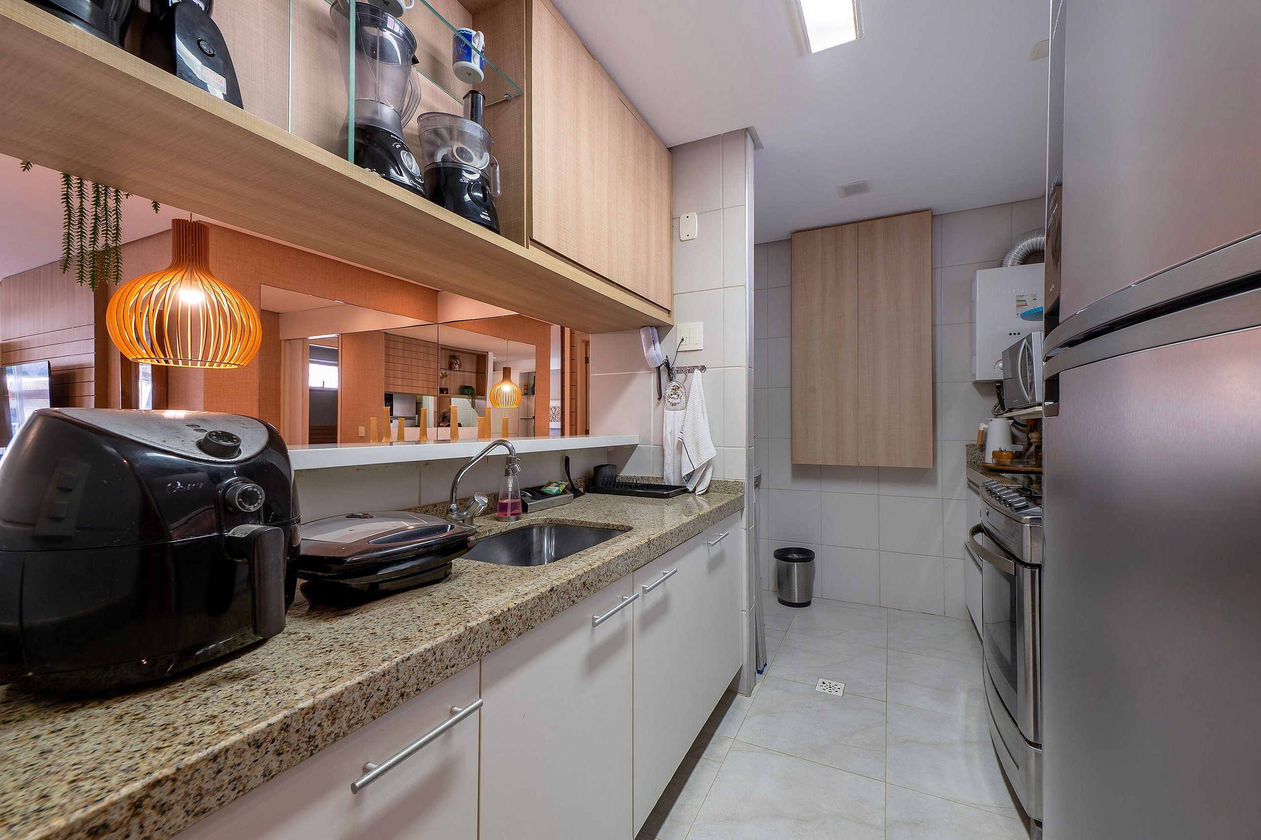 Una cocina moderna con encimeras de granito, electrodomésticos de acero inoxidable y una lámpara colgante.
