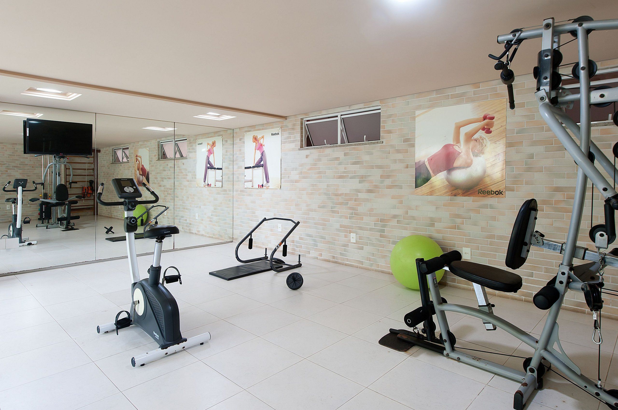 Uma academia com equipamentos de exercícios, um espelho e um anúncio da Reebok.