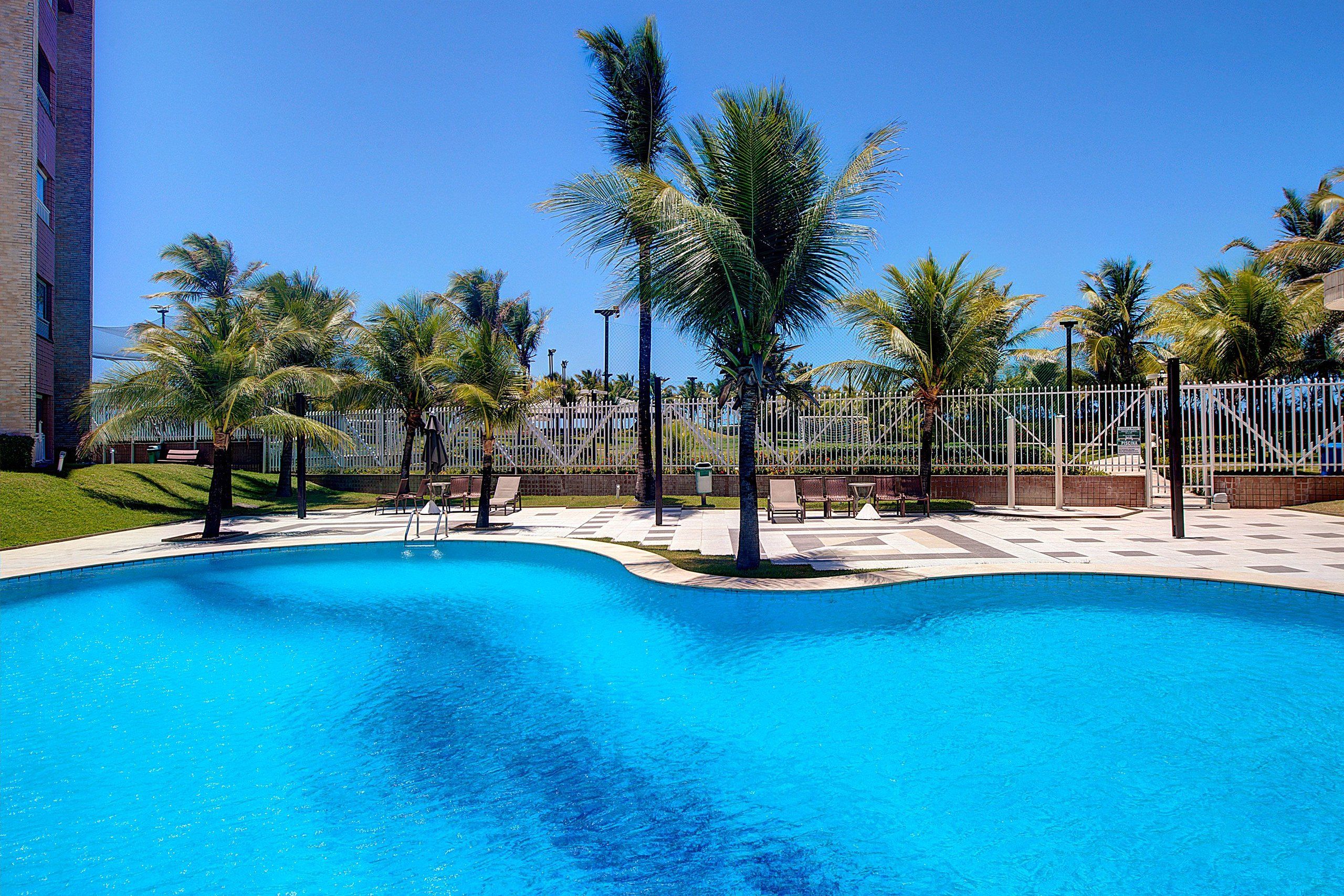 A swimming pool with palm trees and a fence.
