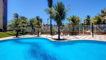 A swimming pool with palm trees and a fence.