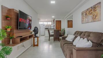 Una sala de estar moderna con televisor de pantalla plana, un sofá marrón y una zona de comedor con una mesa y sillas.