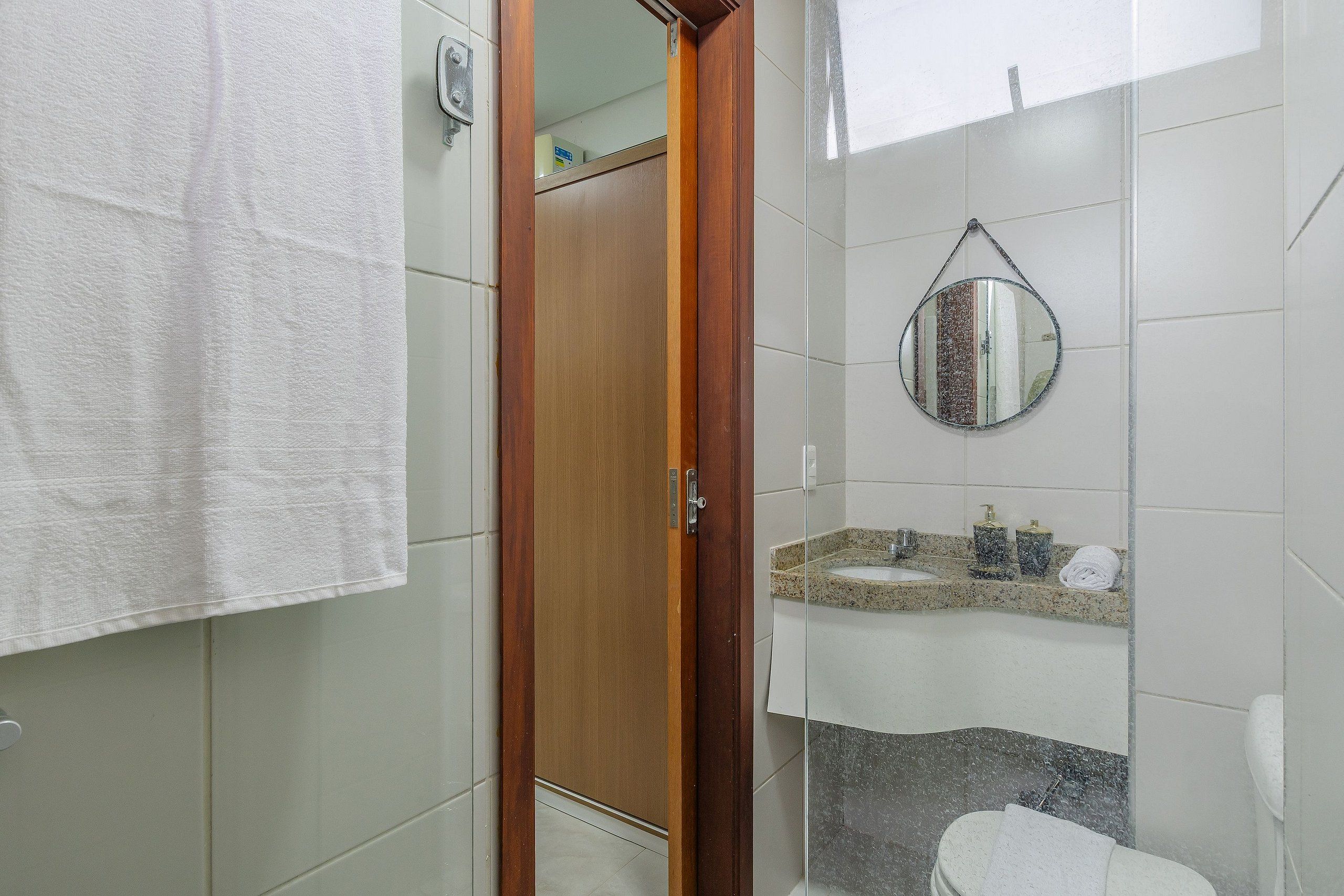 Un baño con puerta de madera, un lavamanos con espejo y un inodoro.