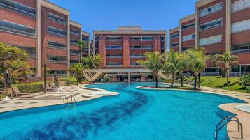 Un hotel con piscina central, varios balcones y un jardín ajardinado.