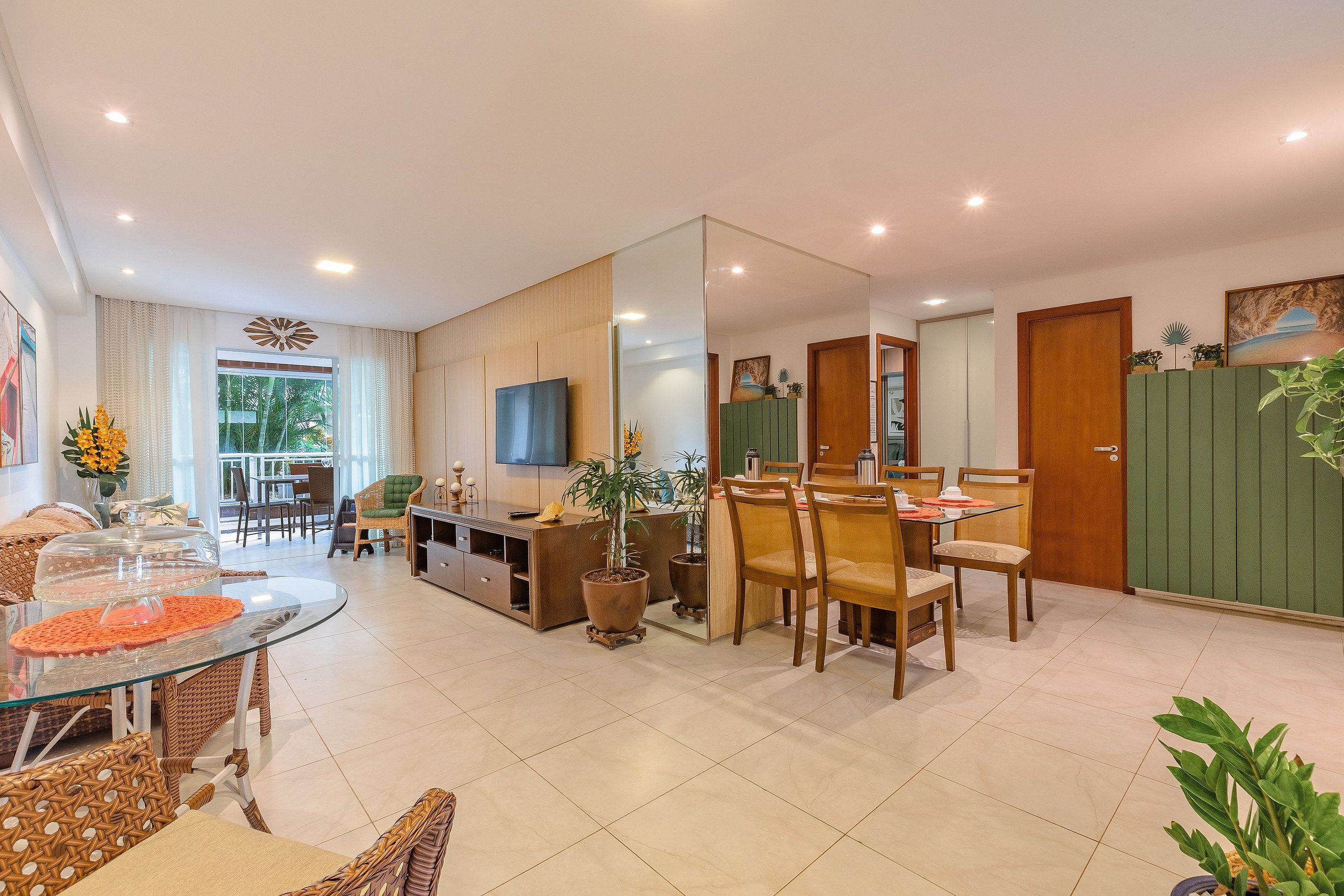Uma sala de estar moderna com área de jantar, televisão e um espelho grande.
